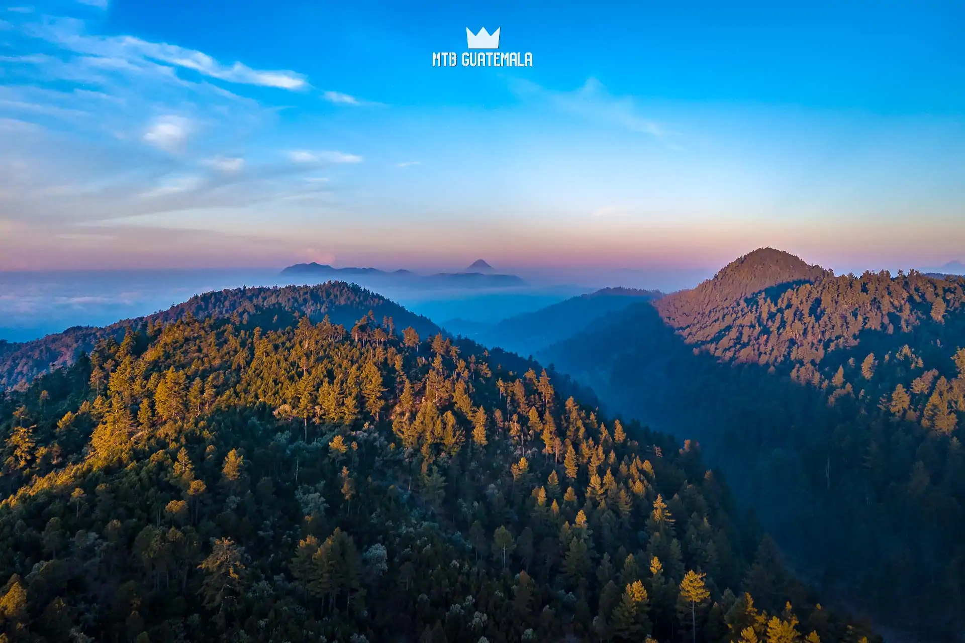 Sun strikes the mountains looking west towards Quetzaltenango and Volcán Santa Maria. Communal forest Totonicapán, Guatemala